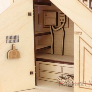 Op de afbeelding: Een houten model van een huis met een open deur die een kleine binnenruimte onthult. De binnenruimte heeft planken, een klein bankje en een deur met een klein raam. Het model is gemaakt van licht hout en heeft een natuurlijke afwerking.