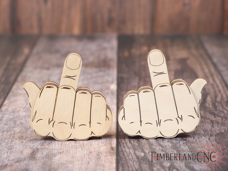 Op de afbeelding: Twee houten hand-uitsparingen met de middelvinger omhoog, een populair gebaar van uitdaging. De uitsparingen zijn gemaakt van lichtbruin hout en liggen op een houten oppervlak.