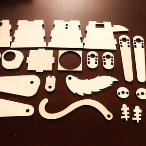 以下が含まれることがあります： DIYクラフトプロジェクト用のレーザーカット木製パーツセット。パーツは正方形、長方形、円形、曲線など、さまざまな形とサイズがあります。パーツは明るい色の木で作られており、滑らかな仕上がりです。