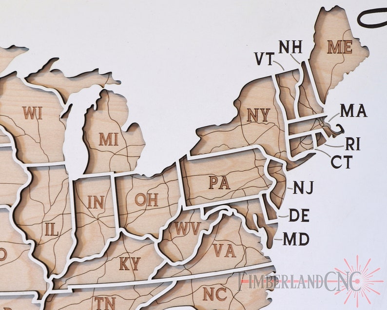 May include: A wooden map of the United States with each state outlined and labeled. The map is made of light brown wood with white outlines. The states in the Northeast are highlighted.