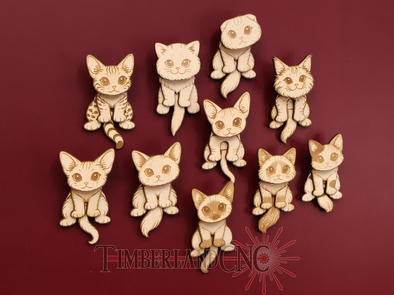 May include: A collection of ten wooden cat cutouts in various poses. Each cat has a unique design, with detailed facial features and markings. The cats are arranged on a deep red background. The text "TIMBERLAND CNC" is at the bottom.