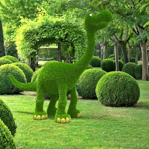 May include: A green topiary dinosaur sculpture in a garden setting. The dinosaur is surrounded by green bushes and trees.