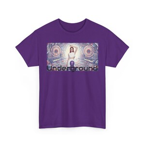 Puede incluir: Camiseta morada con un gráfico que dice "Underground". El gráfico muestra a una persona con ropa blanca, sobre un fondo de maquinaria y teclados, en un estilo futurista.