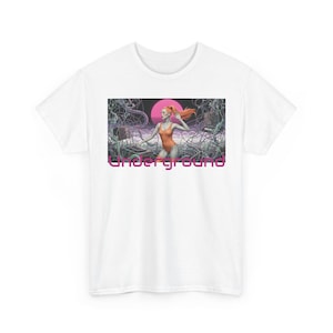 Puede incluir: Camiseta blanca con un gráfico retro. El diseño muestra a una mujer con un body naranja, un sol rosa y la palabra "Underground" en rosa. El fondo incluye formas abstractas y equipos de música.
