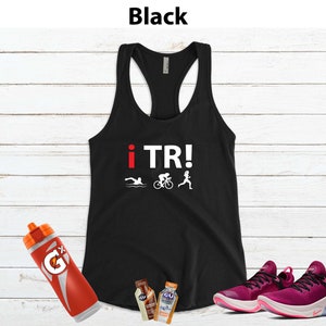 May include: Black racerback tank top with the text "i TR!" and triathlon icons. Includes a red Gatorade bottle, two GU energy gel packets, and a pair of pink running shoes.