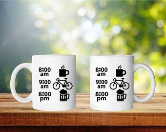 Puede incluir: Dos tazas de cerámica blanca con texto negro e iconos. El texto en las tazas dice "8:00 am", "9:00 am" y "8:00 pm". Los iconos representan una taza de café, una bicicleta y una jarra de cerveza.