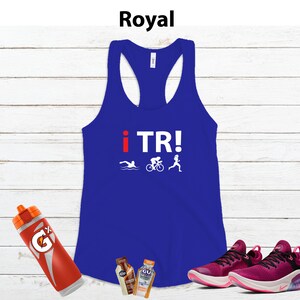May include: Royal blue racerback tank top with the text "i TR!" and triathlon icons. A red and orange Gatorade bottle, two GU energy gel packets, and a pair of pink and black athletic shoes are also in the image.