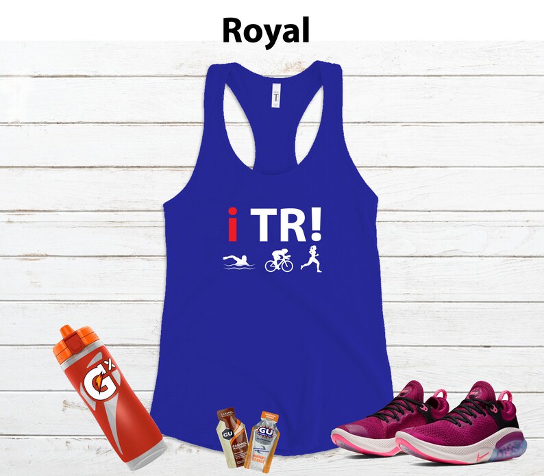 May include: Royal blue racerback tank top with the text "i TR!" and triathlon icons. A red and orange Gatorade bottle, two GU energy gel packets, and a pair of pink and black athletic shoes are also in the image.