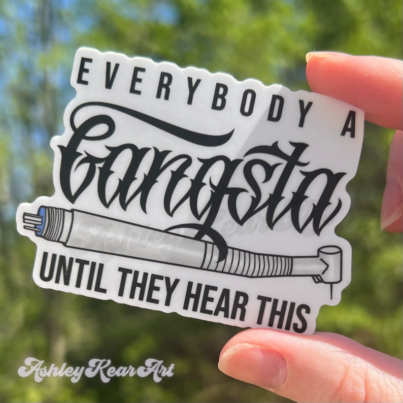 May include: White sticker with black text that reads "Everybody a Gangsta Until They Hear This". A black and white illustration of a dental drill is below the text. The sticker is being held by a hand.