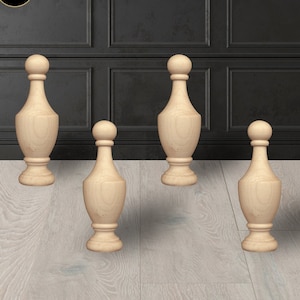 May include: Four wooden finials in a light wood color. The finials are shaped like a vase with a rounded top. They are arranged in a row on a light wood floor.