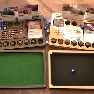 May include: Two wooden tabletop gaming organizers with dice, cards, and felt-lined trays. One organizer is brown, the other is light wood. The brown organizer has the text "FEAR HOPE". Dice are scattered around the organizers.