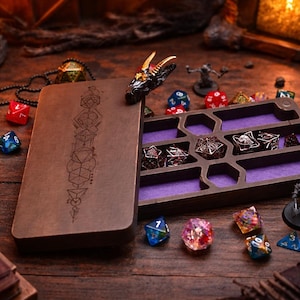 Può includere: Un portadadi in legno con un design geometrico e un interno in velluto viola, aperto per rivelare diversi dadi poliedrici. Una testa di drago adorna la scatola. Vari dadi colorati e figurine in miniatura sono sparsi su una superficie di legno.