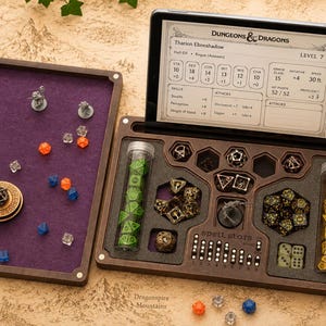 May include: A dark wood tabletop gaming organizer with a purple felt-lined rolling tray, a tablet stand displaying a Dungeons & Dragons character sheet, two clear tubes filled with polyhedral dice, and various metal dice and miniature figures.
