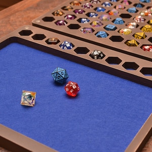 May include: A wooden dice tray with a blue felt lining and a set of dice. The tray has a compartment for storing dice and a separate area for rolling. The dice are a variety of colours and sizes.