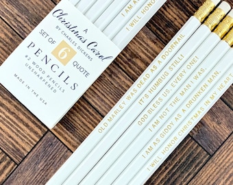 Peut inclure: Un ensemble de six crayons blancs avec des gommes dorées et des citations de "Un chant de Noël" de Charles Dickens. Les crayons sont dans une boîte blanche avec le texte "A Christmas Carol" et "Set of 6 Pencils". Les crayons ne sont pas taillés.
