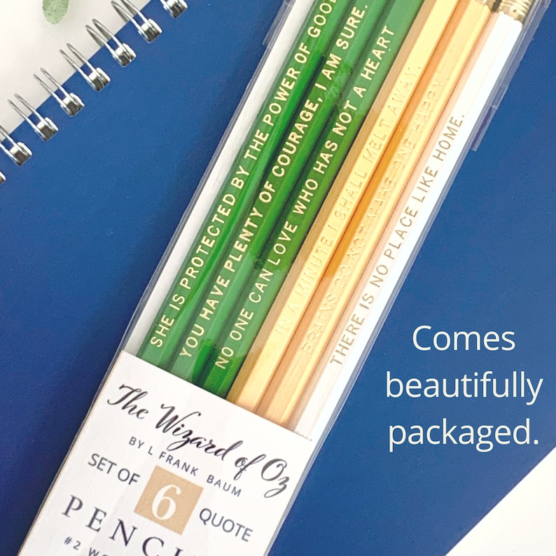 May include: A set of six pencils in a clear plastic case, featuring quotes from "The Wizard of Oz." The pencils are green and yellow with gold lettering. The packaging includes the text "The Wizard of Oz" and "Comes beautifully packaged."