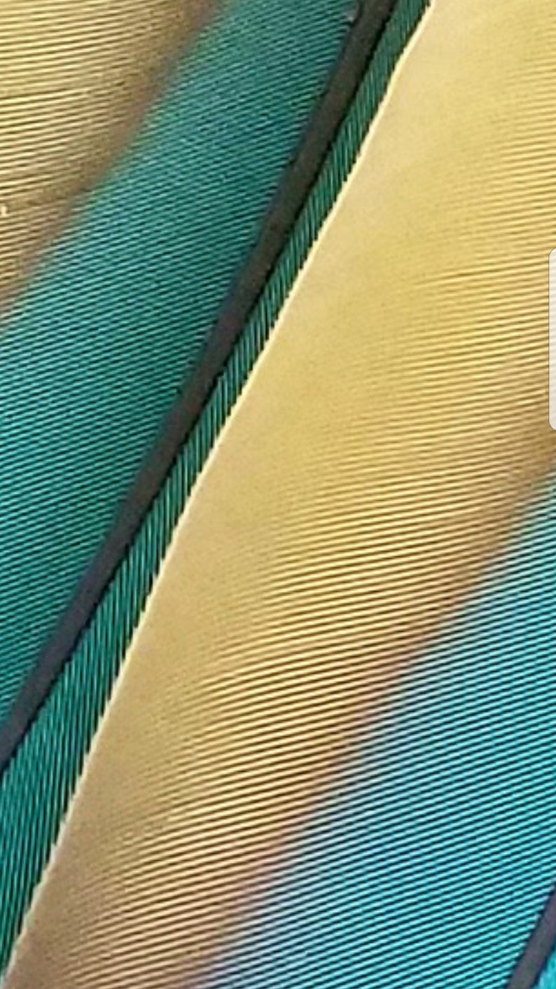 Puede incluir: Imagen abstracta de una superficie texturizada con l&iacute;neas diagonales en tonos turquesa, dorado y negro. Las l&iacute;neas crean un patr&oacute;n, sugiriendo una tela o un elemento decorativo.