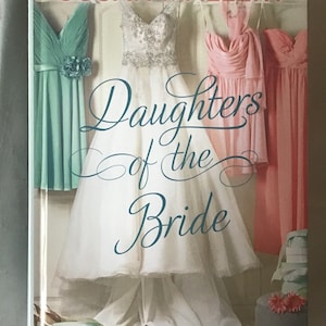 May include: Book cover featuring a white wedding dress, three bridesmaids dresses in shades of pink and teal, and the title "Daughters of the Bride" by Susan Mallery.