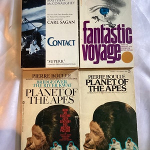 May include: A collection of five paperback books, all science fiction novels. The books are arranged vertically, with the titles "Contact", "Fantastic Voyage", "Planet of the Apes", "Planet of the Apes", and "Bridge Over the River Kwai".