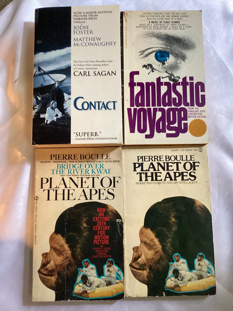 May include: A collection of five paperback books, all science fiction novels. The books are arranged vertically, with the titles "Contact", "Fantastic Voyage", "Planet of the Apes", "Planet of the Apes", and "Bridge Over the River Kwai".
