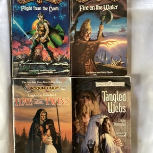 May include: Four fantasy novel covers. The first two are from the Lone Wolf series, titled "Flight from the Dark" and "Fire on the Water". The third is from the Dragonlance series, titled "Time of the Twins". The fourth is from the Forgotten Realms series, titled "Tangled Webs".