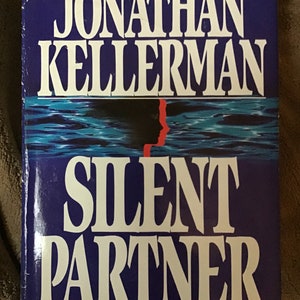 May include: A blue book cover with the title "Silent Partner" by Jonathan Kellerman. The book is an Alex Delaware novel.