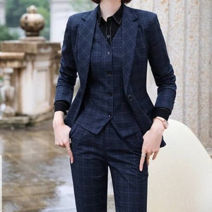 May include: A navy blue plaid pantsuit with a matching vest. The jacket has a notched collar and a single button closure. The pants have a straight leg.