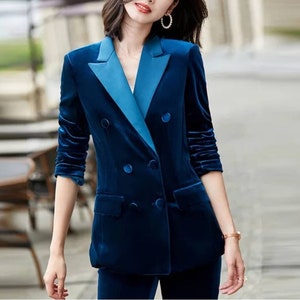 May include: A navy blue velvet blazer with a contrasting light blue lapel and buttons. The double-breasted jacket has long sleeves and a tailored fit, suggesting a formal or business attire style.