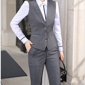 May include: A gray business suit with a vest and matching pants. The vest has a V-neck and four buttons. The suit is made of a textured fabric.