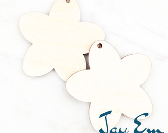May include: Two unfinished wooden flower-shaped ornaments with a hole at the top for hanging. The ornaments are 1.5 inches in size. The text "Jay Em Laser Designs" is visible at the bottom of the image.