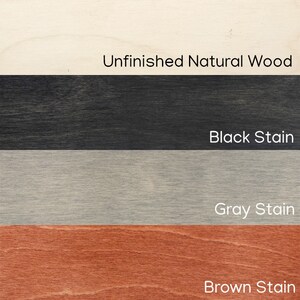 Pu&ograve; includere: Un campione di finiture del legno, tra cui Legno Naturale non Finito, Macchia Nera, Macchia Grigia e Macchia Marrone. Il testo etichetta ogni finitura. L'immagine mostra i diversi colori e le trame del legno.