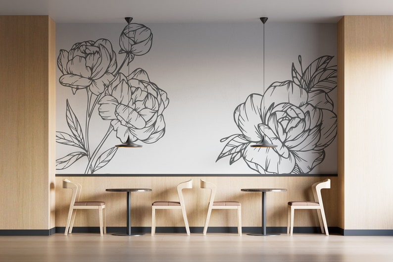 May include: A minimalist dining area with four chairs and two round tables. The walls are decorated with a black and white floral design. The chairs are made of light wood and have a simple design. The tables are also made of light wood and have a black metal base.