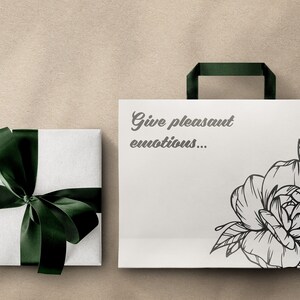 May include: A white gift bag with a black and white floral design and the text "Give pleasant emotions..." printed on the front. The bag has a green ribbon handle.
