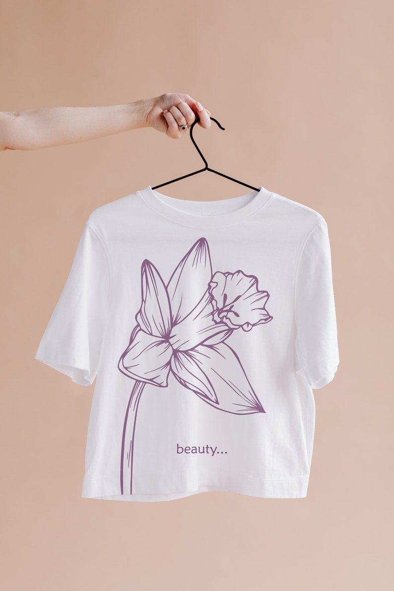 May include: White t-shirt with a purple line drawing of a flower and the text "beauty..." printed on the front.