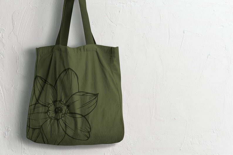 May include: A green canvas tote bag with a black and white floral design. The bag has two long handles.