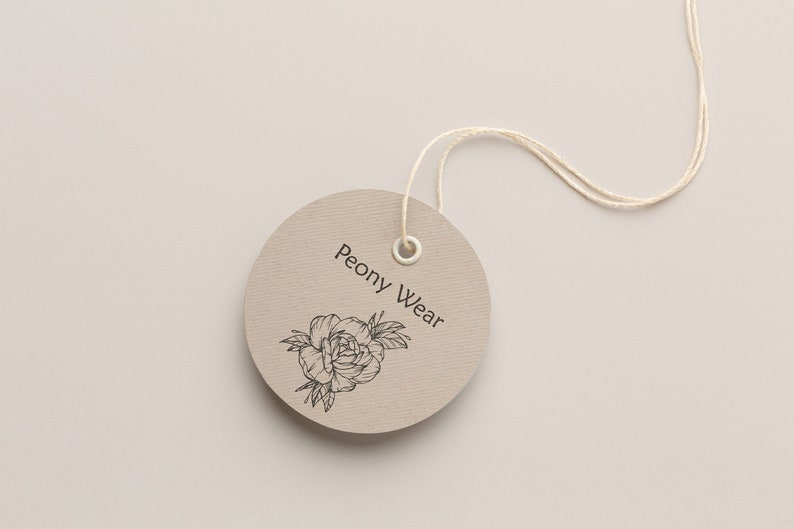 May include: A round, brown paper tag with a white string attached. The tag has a black and white illustration of a peony flower and the text "Peony Wear".