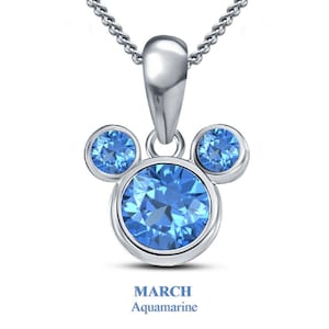Könnte beinhalten: Eine silberne Anhängerkette mit einem Mickey Mouse-inspirierten Design, besetzt mit drei hellblauen Aquamarin-Edelsteinen. Der Text "MÄRZ Aquamarin" ist darunter abgebildet.