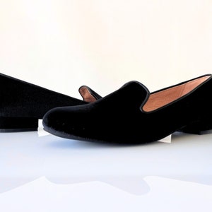 K&ouml;nnte beinhalten: Ein Paar schwarze Samt-Slipper mit niedrigem Absatz. Die Slipper sind aus weichem, pl&uuml;schigem Samt gefertigt und haben ein klassisches, elegantes Design.