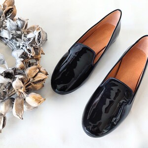 "Glossy black leather slip-on loafers with a low heel, suitable for all-day wear during office hours or elegant evening events."