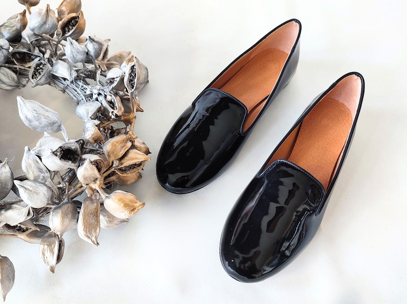 "Glossy black leather slip-on loafers with a low heel, suitable for all-day wear during office hours or elegant evening events."