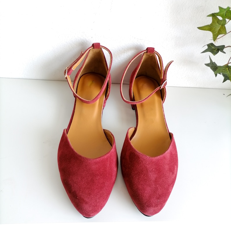 May include: A pair of burgundy suede ankle strap shoes with a pointed toe.
