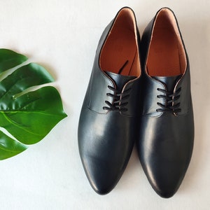 Puede incluir: Un par de zapatos negros de cuero con cordones y puntera puntiaguda.