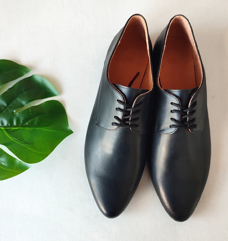 Puede incluir: Un par de zapatos negros de cuero con cordones y puntera puntiaguda.