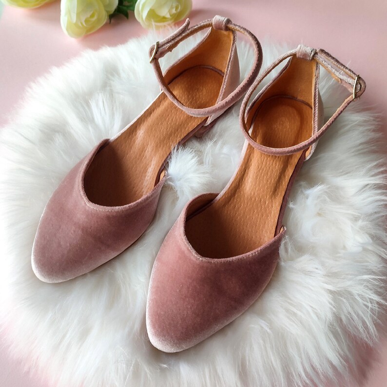 May include: A pair of dusty rose velvet ankle strap flats with a pointed toe.