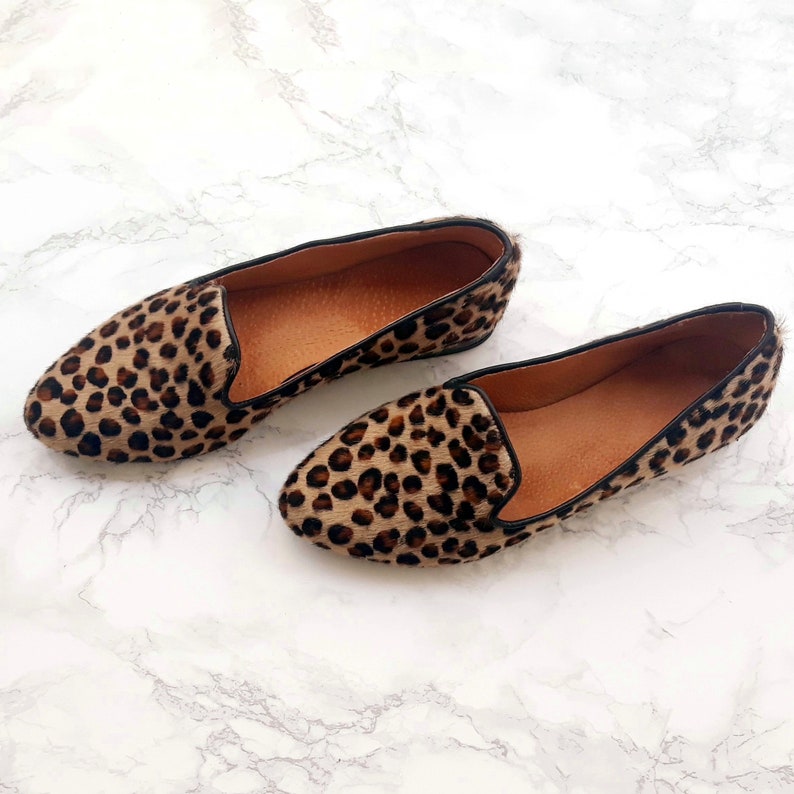 May include: A pair of brown and black leopard print slip-on shoes.