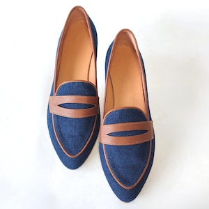 May include: A pair of blue denim loafers with brown leather accents. The loafers have a pointed toe and a slip-on design.