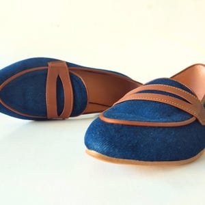 May include: A pair of blue denim loafers with brown leather accents. The loafers have a pointed toe and a low heel.