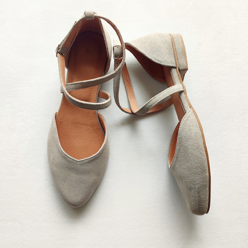 May include: A pair of gray suede ankle strap sandals with a pointed toe.
