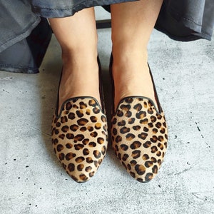 May include: A pair of brown and black leopard print flats with a pointed toe.