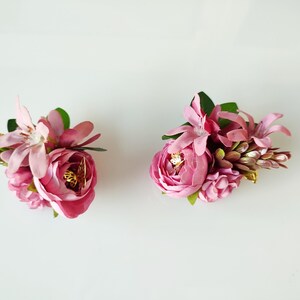 May include: Two pink flower arrangements with green leaves and gold accents. The flowers are arranged in a cluster and are perfect for adding a touch of elegance to any occasion.